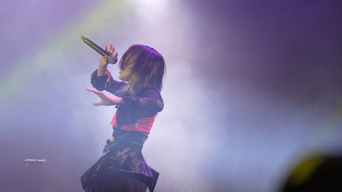 Cantora no palco, envolta em fumaça e luz violeta
